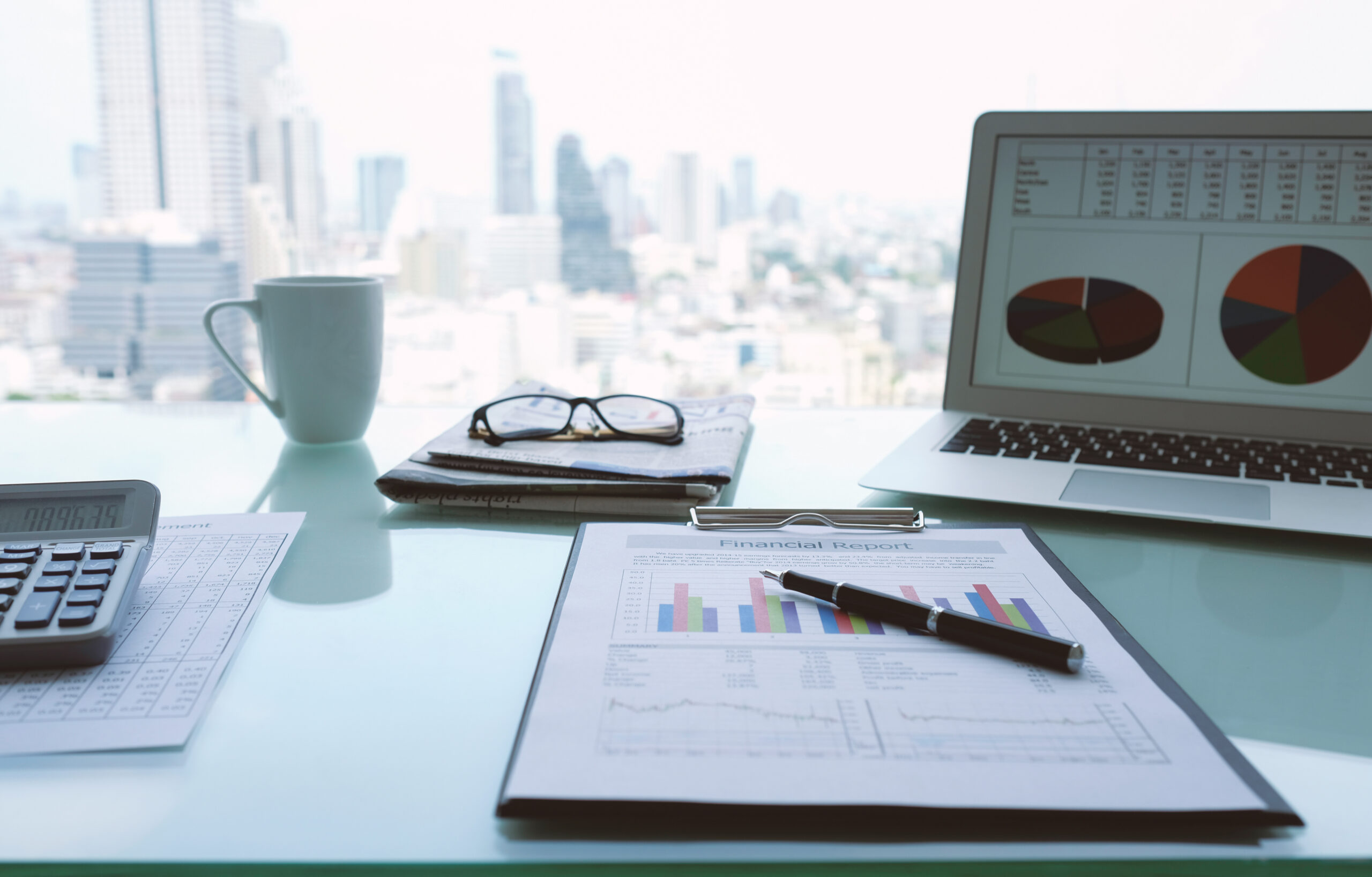 an office desk with laptop, calculator and financial report.